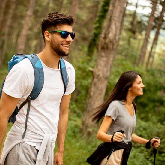 Smiling young couple hiking in the forest.